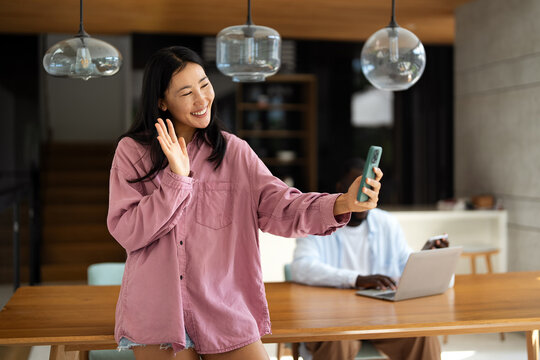 A happy smiling Asian woman using digital device, mobile phone for video call, selfie and fun - Powered by Adobe