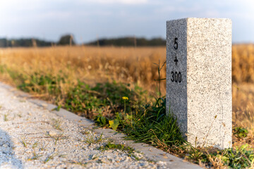 Granite Milestone Beside Rural Road In Autumn Landscape For Navigation And Infrastructure Themes