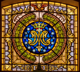 Obraz premium SALERNO, ITALY - OCTOBER 6, 2025: The the stained glass with the marianic initials in the church Chiesa della Santissima Annunziata by unknown artist. 