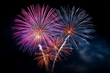 Fototapeta premium FIREWORKS IN PINK, BLUE AND ORANGE ON A BLUE SKY