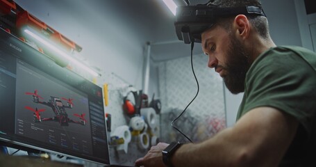 Bearded Man in Tactical Gear Deeply Focused, Using Computer Display and FPV Gear While Working on Drone Electronics. Engineer Utilizing Digital and Physical Tools. Dedication to Military Grade Tech.