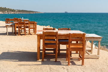 Wooden table and chairs on a beach by the Mediterranean Sea.