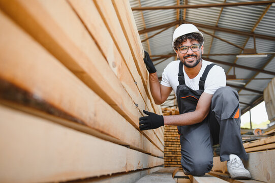 Woodworker inspecting lumber in warehouse, quality control and timber selection