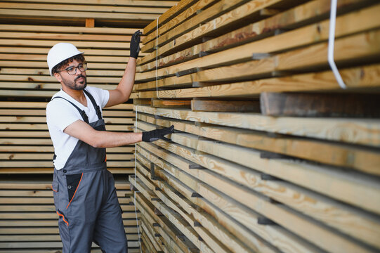 Carpenter inspecting wooden planks in lumber warehouse