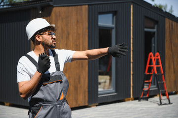 Construction worker directing modular house placement onto truck