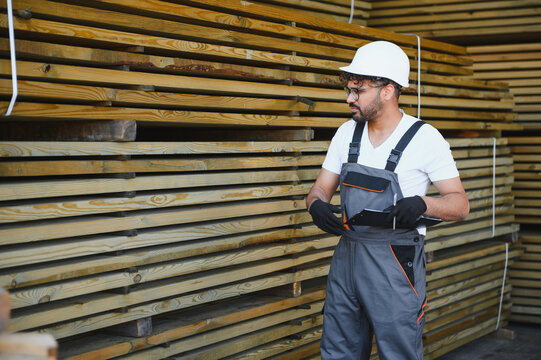 Warehouse worker inspecting lumber inventory and taking notes