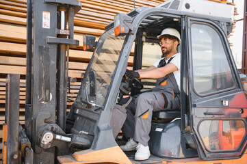 Warehouse worker driving forklift in lumber storage area
