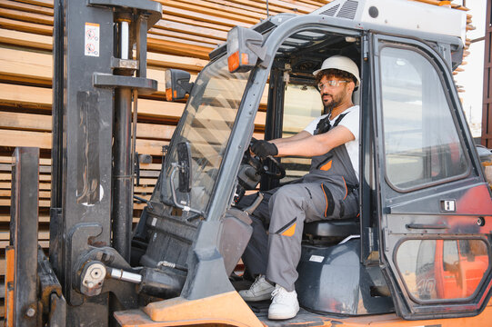 Warehouse worker driving forklift in lumber storage area - Powered by Adobe