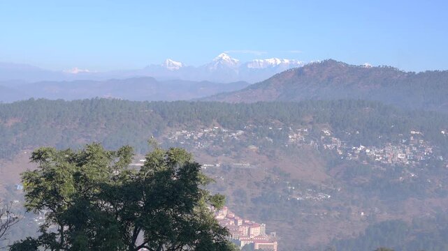 Wide angle view of Almora city sprawl on hills with majestic Himalayan snow peaks in background, sunny day in Uttarakhand 4K