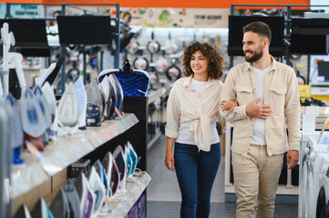 Couple choosing home appliances walking in electronics store