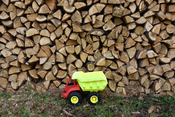 Plastic toy dump truck in front of a firewood stack