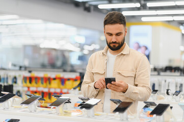 Customer comparing smartphones using his phone in electronics store