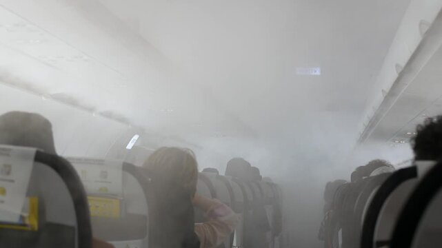 interior inside airplane aeroplane's cabin while flying with shaking and many smoke mist fog in the plane's cabin.emergency situation on the airplane while operating