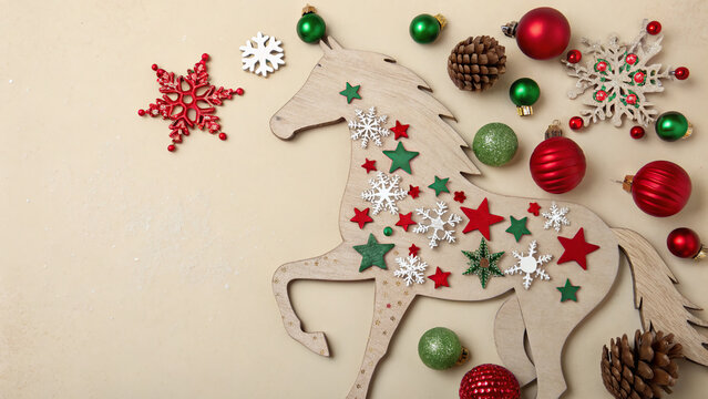 Decorated wooden unicorn surrounded by festive ornaments and holiday decorations on a neutral background