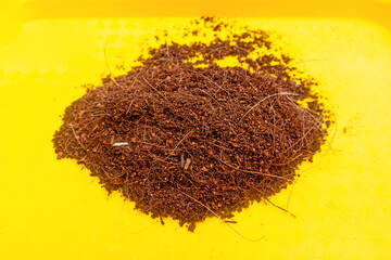 Close up of Coco peat on yellow background, organic planting media, soil fertilizer substrate dry material