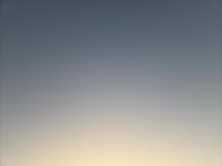 a minimalist, seamless sky background showing a soft gradient transition from a muted blue-grey at the top to a pale yellow-beige or light orange at the bottom, characteristic of twilight.