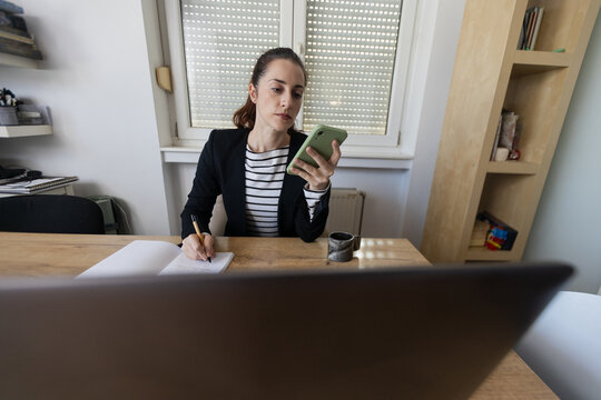 Woman multitasking working from home using smartphone