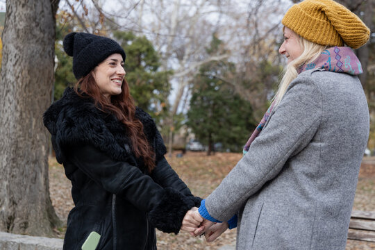 Two smiling women hugging, sharing joy and friendship in an autumn park - Powered by Adobe