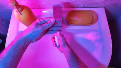 Human hands are turning the home faucet on and washing it with soap and clean tap water for good personal hygiene.