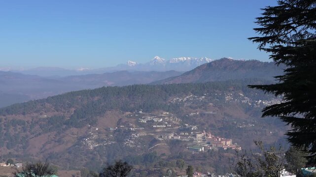 Scenic view of Almora city and Himalayan peaks from Bright End Corner, sunny day with pine tree framing, Uttarakhand 4K