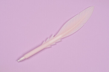 A light pink, feather-shaped ballpoint pen is positioned diagonally across a simple, uniform lilac background