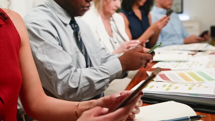 Diverse Business Professionals Engaged with Smartphones During a Corporate Meeting - Powered by Adobe