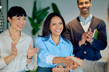 Happy business people applauding a colleague's handshake, symbolizing welcome, achievement, and collaboration within a diverse company