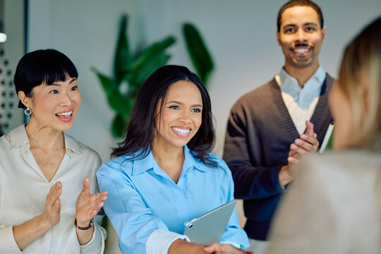 Business professionals congratulating a colleague with a handshake and applause, recognizing a successful agreement or new partnership