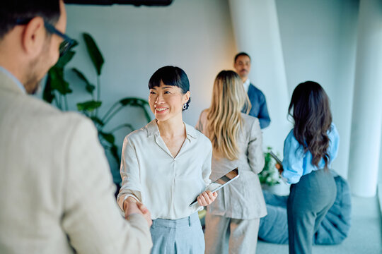 Diverse business professionals shaking hands during a meeting, representing successful collaboration, partnership, and agreement in a modern office setup