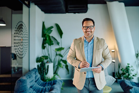Happy professional man in a contemporary workplace using a portable device, showcasing innovation, confidence, and digital lifestyle