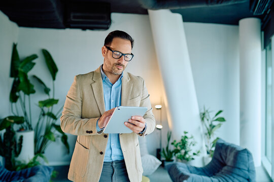 Determined businessman engaged with a tablet in a well-lit office lounge, networking, completing tasks, and strategizing