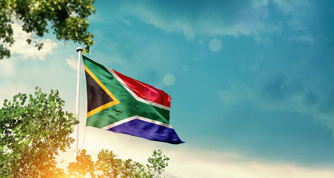 South Africa national flag waving in the sky behind the tree. The flag blowing with beautiful sunlight. South Africa national flag for independence day.