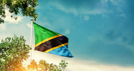 Tanzania national flag waving in the sky behind the tree. The flag blowing with beautiful sunlight. Tanzania national flag for independence day.