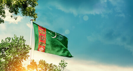 Turkmenistan national flag waving in the sky behind the tree. The flag blowing with beautiful sunlight. Turkmenistan national flag for independence day.