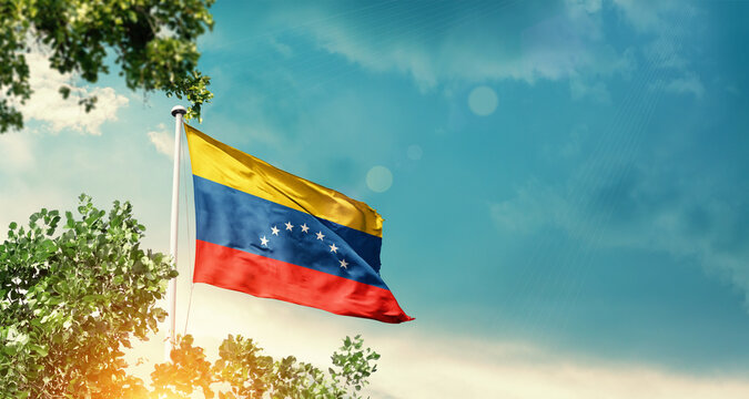 Venezuela national flag waving in the sky behind the tree. The flag blowing with beautiful sunlight. Venezuela national flag for independence day. - Powered by Adobe