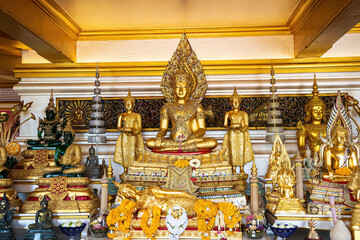 A richly detailed altar featuring multiple golden Buddha statues including a central seated Buddha and a reclining Buddha.
