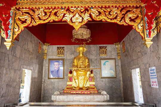 A golden memorial statue displayed inside the temple area of Wat Chana Songkhram, Bangkok, surrounded by traditional Thai architectural details.