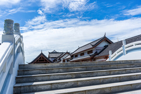 Stone stairway with Chinese architectural roofs viewed under blue sky in Suphanburi