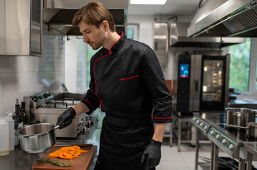 Skilled man working in restaurant standing near stove in culinary space