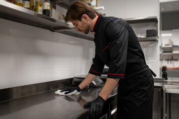 Chef cleaning kitchen counter after cooking in restaurant
