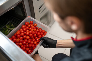 Chef arranging tomatoes in plastic container for cold storage