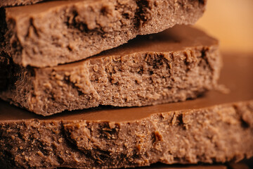 Macro texture of layered porous milk chocolate with rough aerated structure and warm lighting, ideal for confectionery advertising, packaging design and gourmet sweet food visuals