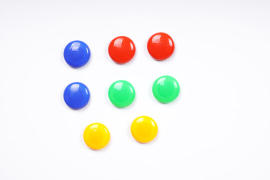 colorful round magnets in blue green red and yellow on white whiteboard background