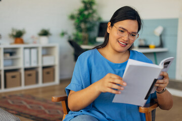 This image shows a happy reader seated in a stylish chair with a book, creating a serene atmosphere in a beautifully designed living room filled with artistic elements.
