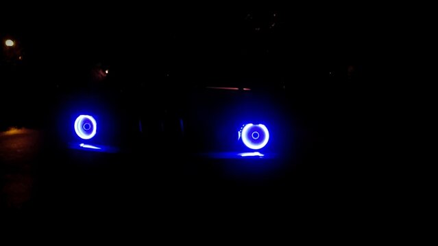 Bright Blue LED Angel Eyes Halo Rings Headlights: Custom Off-Road Car Tuning Lighting in Darkness at Night, Automotive Modification Close-up