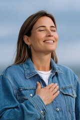 A woman wearing a blue jacket is smiling and hugging her chest