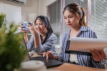 People business team work and learn online from home office, professional colleagues collaborate, one woman diligently focuses on laptop with documents, other happy records video using mobile phone