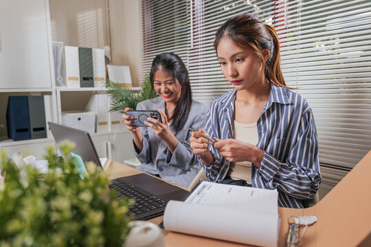 Young business women work online, home office team members learn and collaborate. People focus, one woman reviews monthly planner, other records using smartphone for modern business concepts - Powered by Adobe