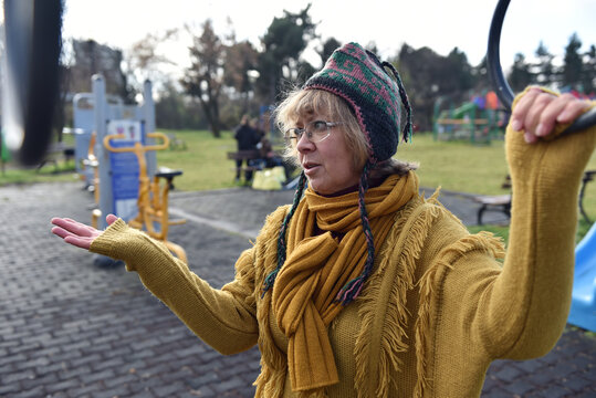 Woman talking in outdoor park wearing a mustard yellow sweater and a knitted hat - Powered by Adobe