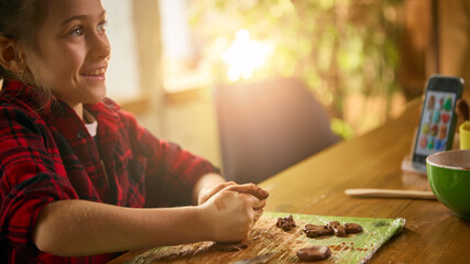 Girl smiling while shaping small clay pieces at table. Concept of joyful creativity, warm learning...